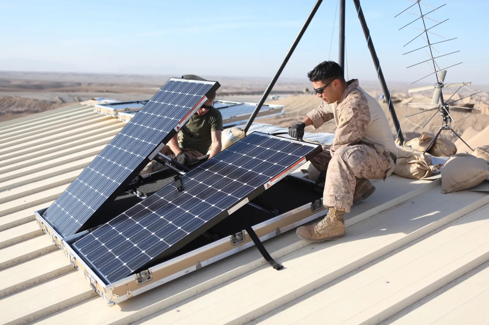 Photo of U.S. military members installing a solar panel on a roof. Image courtesy of U.S. Marine Corps Lance Cpl. Alexander Quiles.