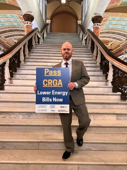 Pass CRGA Lower Energy Bills Now Sign held by SEIA's Andrew Linhares
